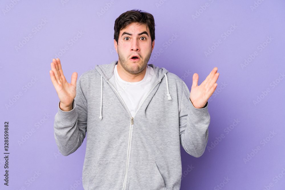 Young man isolated on purple background celebrating a victory or success, he is surprised and shocked. Young man isolated on purple background celebrating a victory or success, he is surprised and shocked.
