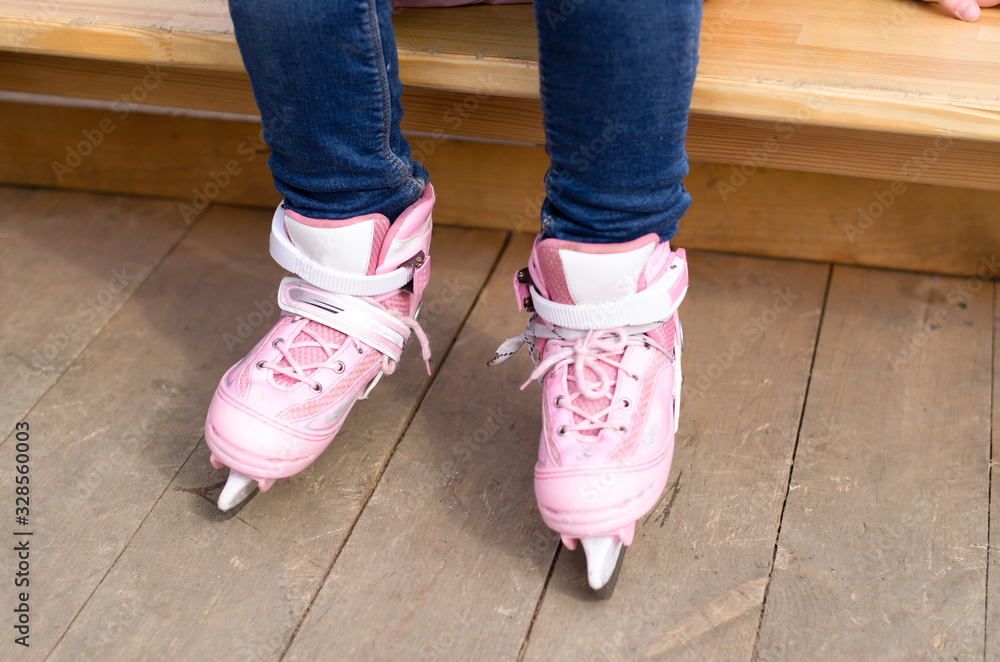 Girl's pink ice skates on the ice rink