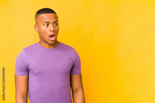 Young latin man isolated on yellow background being shocked because of something she has seen.