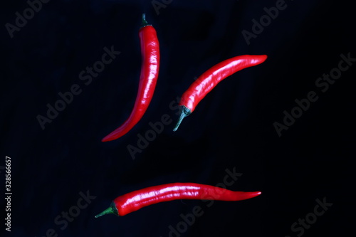 red juicy peppers in the air on a dark background