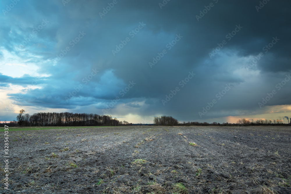 Dark rainy clouds over a plowed field