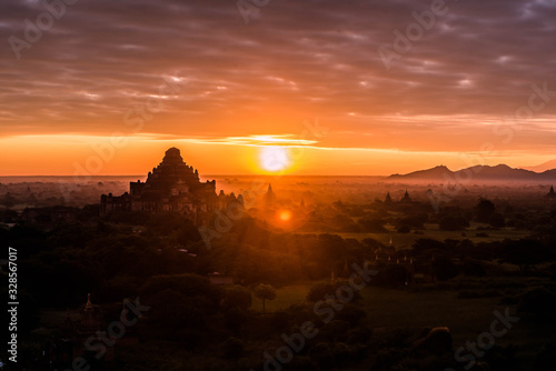 Sunrise above old pagodas misty with amazing clouds early morning and air balloons at Bagan, Myanmar.