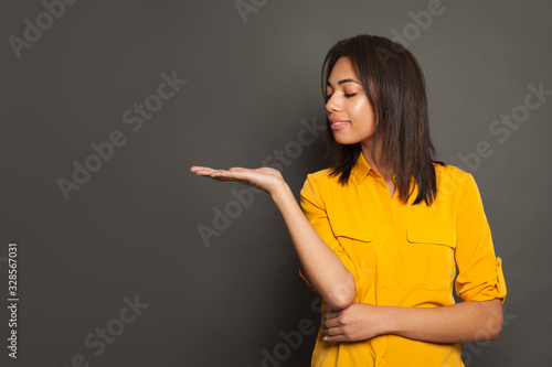 Cute young black woman student looking at her empty open hand