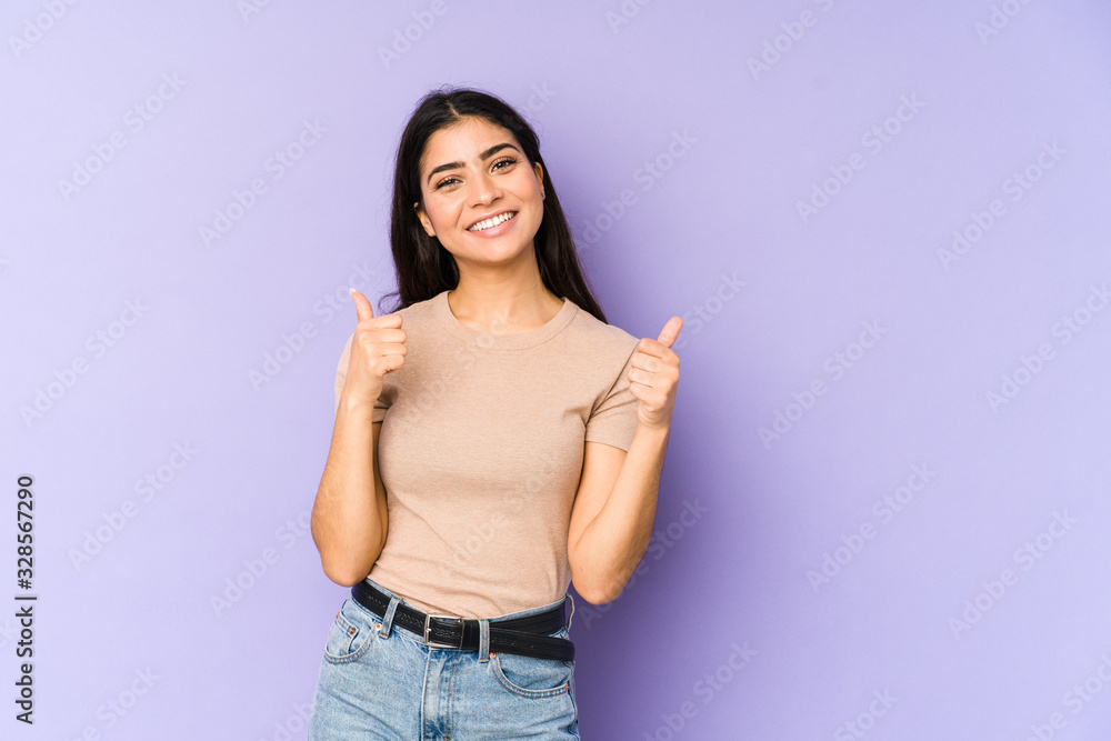 Young indian woman isolated on purple background raising both thumbs up, smiling and confident. Young indian woman isolated on purple background raising both thumbs up, smiling and confident.