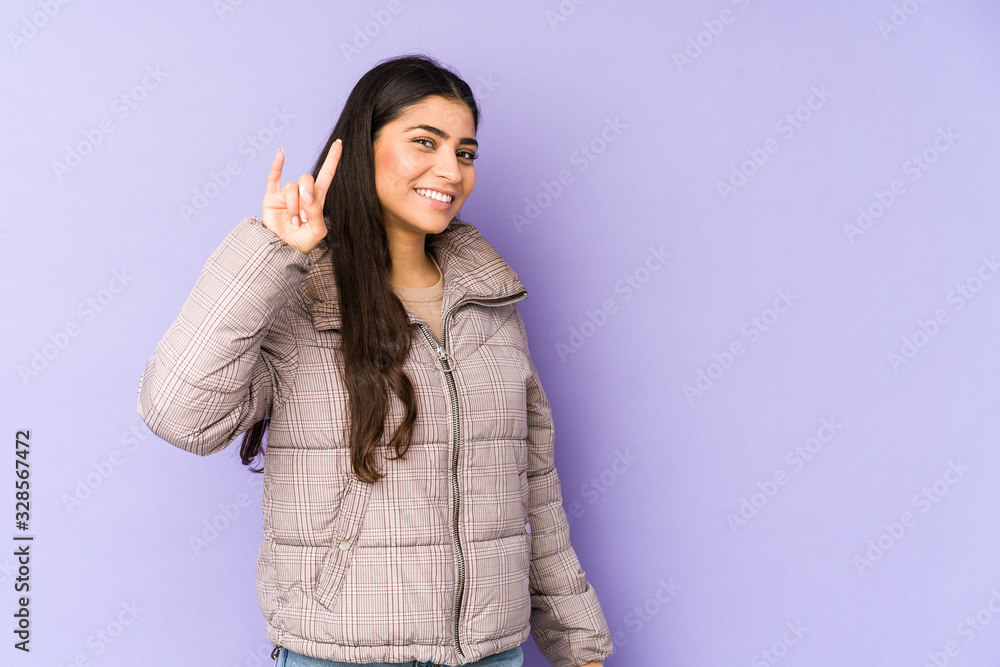 Young indian woman isolated on purple background showing a horns gesture as a revolution concept. Young indian woman isolated on purple background showing a horns gesture as a revolution concept.