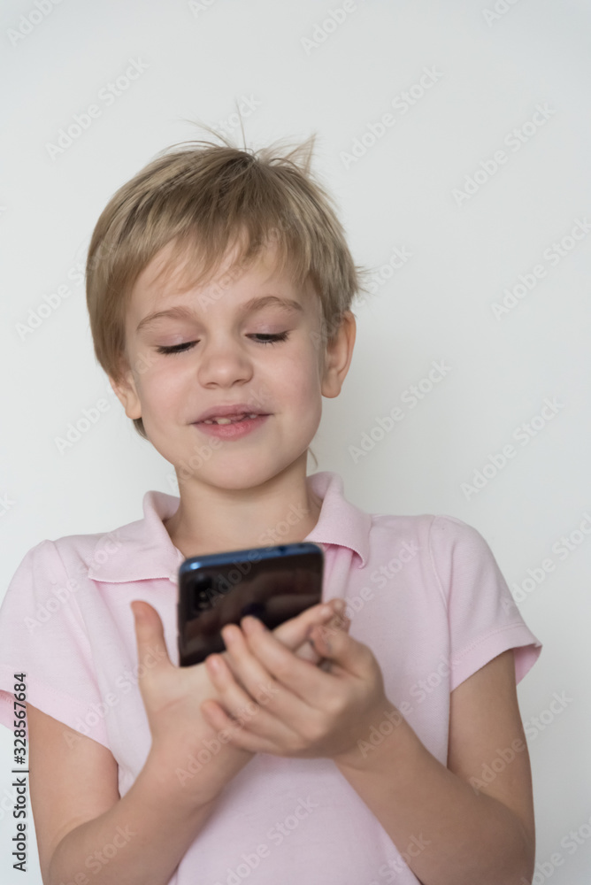 A cute child is laughing loudly, holding a cell phone in his hand. A cute child is laughing loudly, holding a cell phone in his hand.