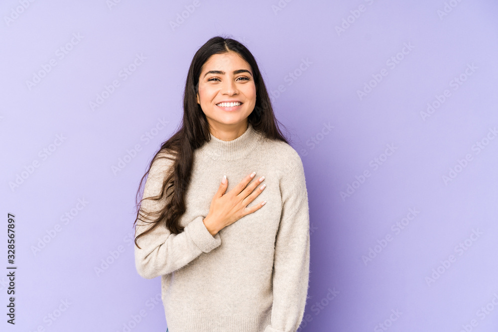 Young indian woman isolated on purple background laughs out loudly keeping hand on chest. Young indian woman isolated on purple background laughs out loudly keeping hand on chest.