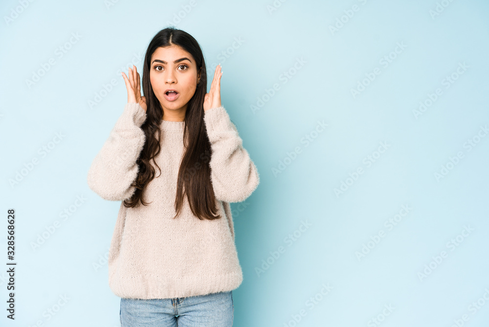 Young indian woman isolated on blue background surprised and shocked. Young indian woman isolated on blue background surprised and shocked.