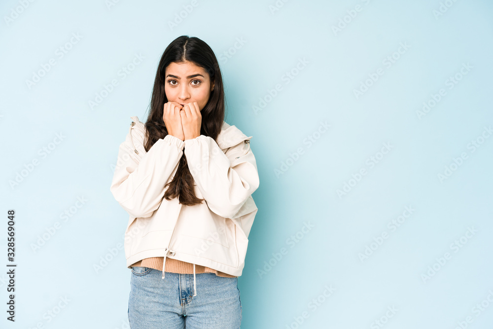 Young indian woman on blue background biting fingernails, nervous and very anxious. Young indian woman on blue background biting fingernails, nervous and very anxious.