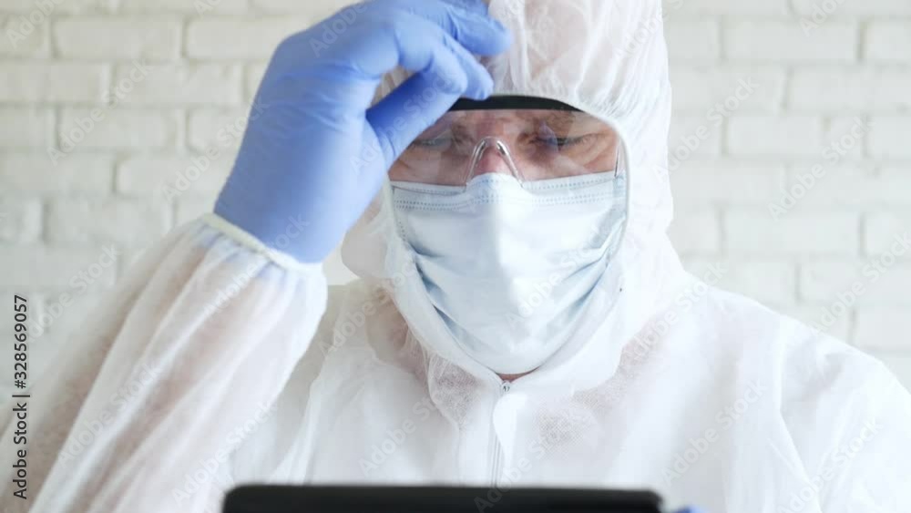 Slow Motion Doctor Wearing Protection Suit, Gloves, Mask, and Glasses in Hospital Quarantine Using a Mobile Phone Slow Motion Doctor Wearing Protection Suit, Gloves, Mask, and Glasses in Hospital Quarantine Using a Mobile Phone