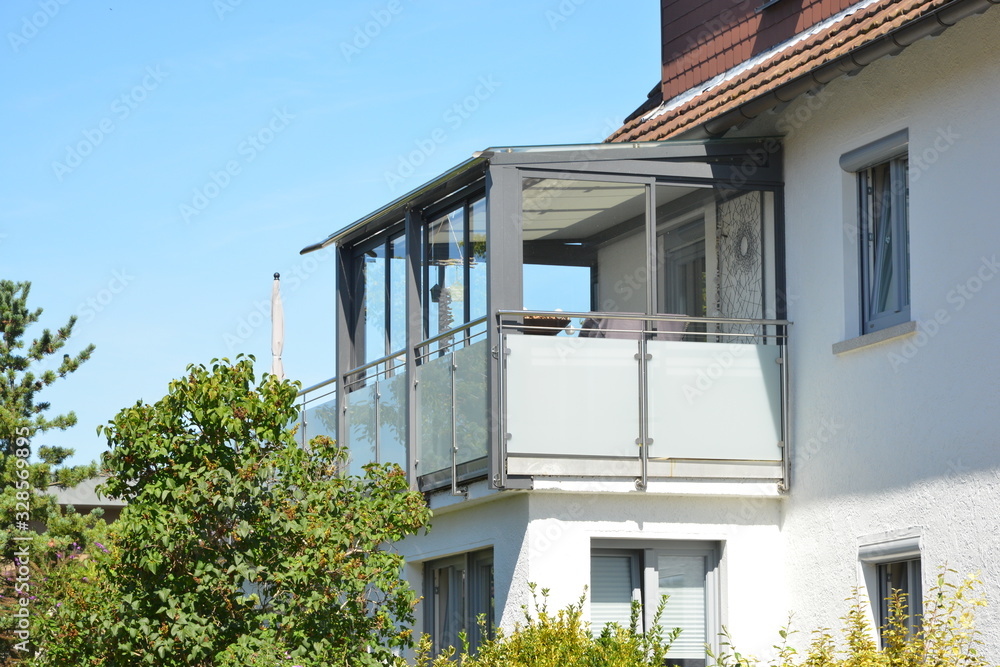 Fototapeta premium Vorgebauter Wintergarten mit dreiseitiger Verglasung an einem Wohnhaus