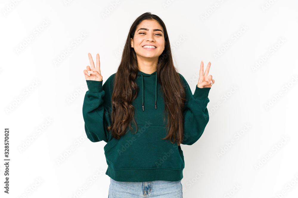Young indian woman isolated on purple background showing victory sign and smiling broadly. Young indian woman isolated on purple background showing victory sign and smiling broadly.