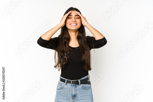 Young indian woman isolated on purple background laughs joyfully keeping hands on head. Happiness concept.