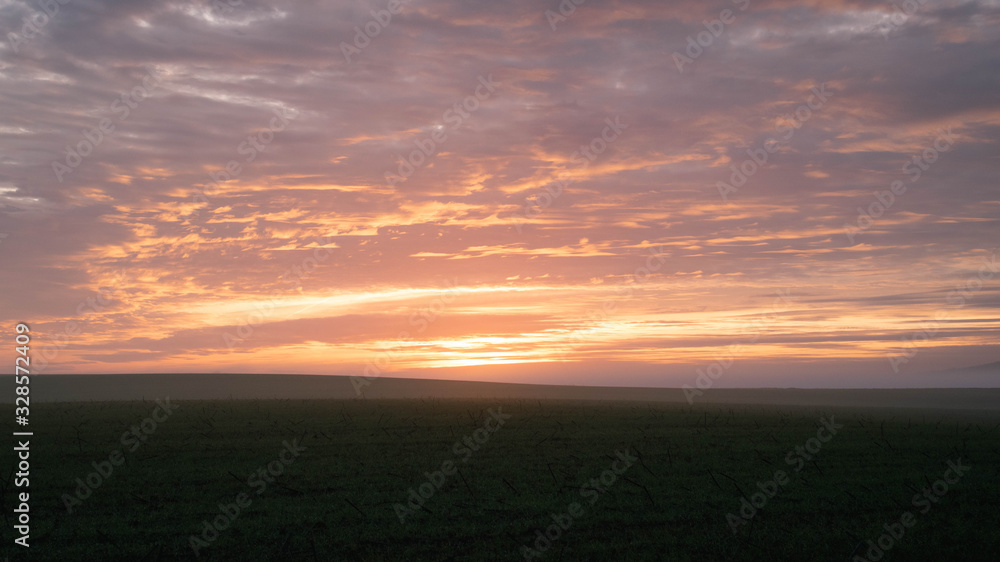 Countryside sunset landscape with agricultural fields. Beautiful orange clouds