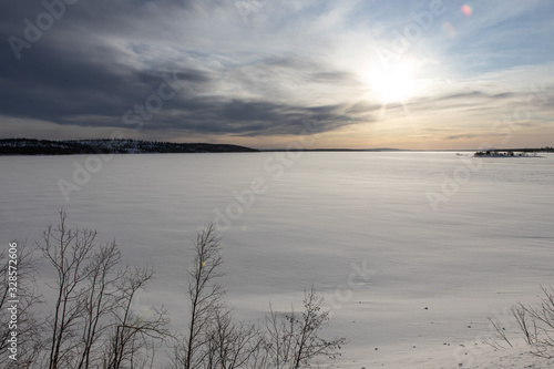 Bright winter sun over a field of ice. The magnificent landscape of the frozen lake. Cold winter background