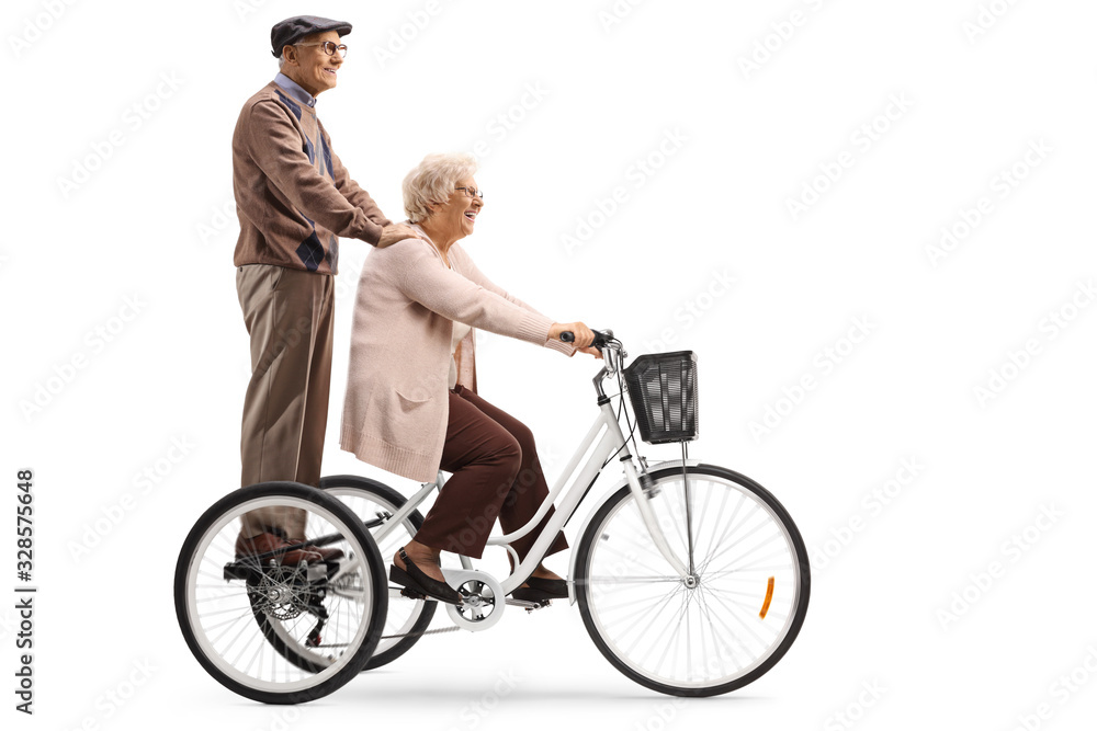 Senior woman riding a tricycle and a senior man standing behindd and holding onto her Senior woman riding a tricycle and a senior man standing behindd and holding onto her