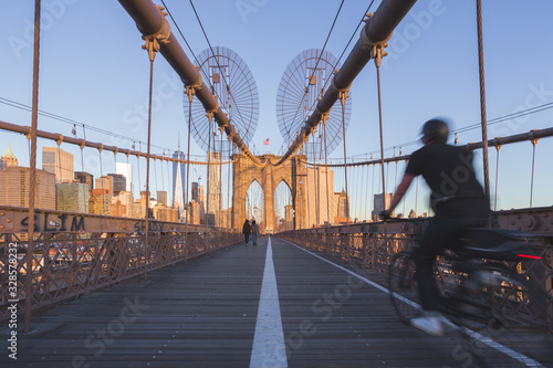 Brooklyn Bridge in a sunny morning with man cycling in New York. © EyesTravelling
