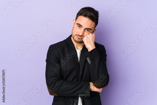 Young caucasian man isolated on purple background who feels sad and pensive, looking at copy space.