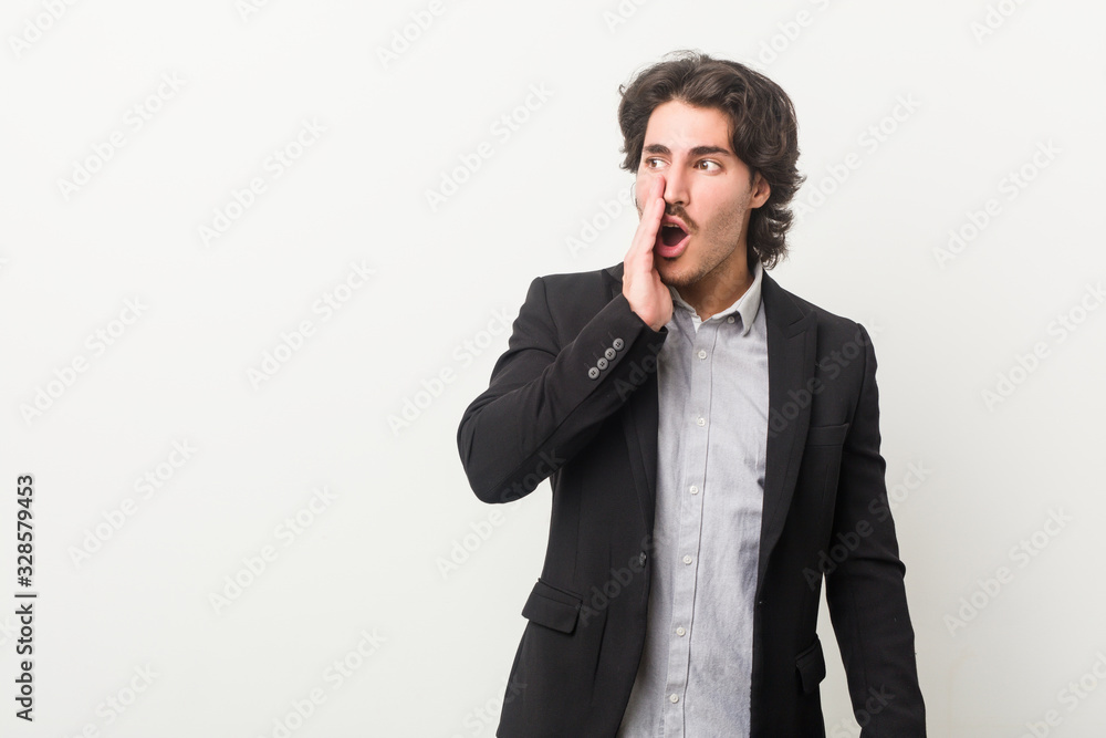 Young business man against a white background is saying a secret hot braking news and looking aside Young business man against a white background is saying a secret hot braking news and looking aside