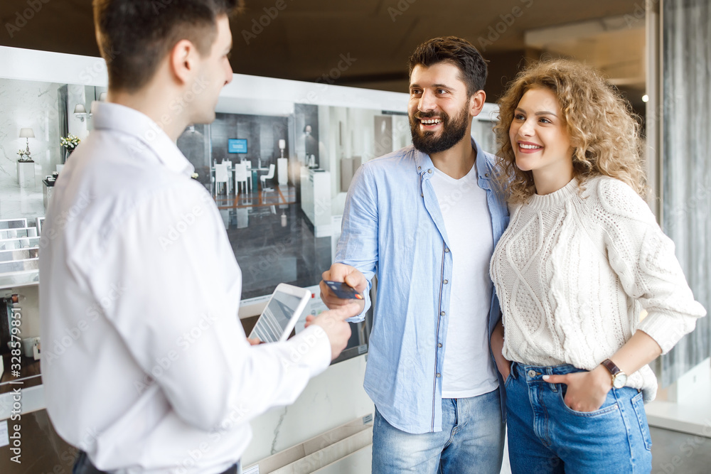 Sale, consumerism, shopping and people concept - happy couple with credit card at decoration store in mall Sale, consumerism, shopping and people concept - happy couple with credit card at decoration store in mall