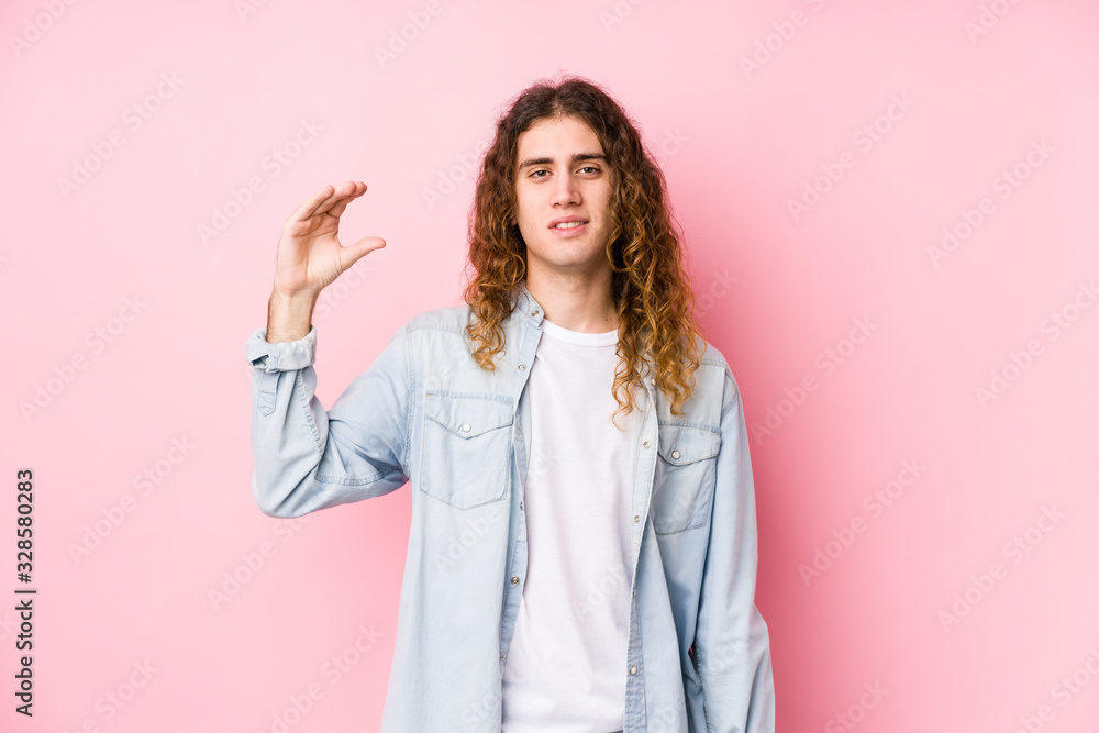 Long hair man posing isolated holding something little with forefingers, smiling and confident. Long hair man posing isolated holding something little with forefingers, smiling and confident.