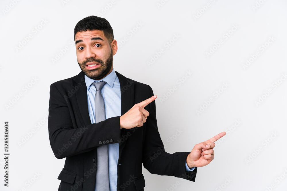 Young latin business woman against a white background isolated shocked pointing with index fingers to a copy space. Young latin business woman against a white background isolated shocked pointing with index fingers to a copy space.