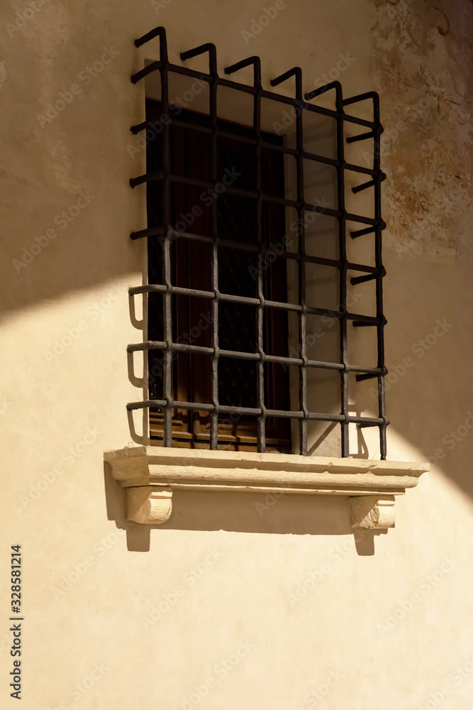 Obraz premium Caratteristica finestra con sbarre in centro storico di antica città . Portogruaro, Veneto, Italia. Fotografia notturna.