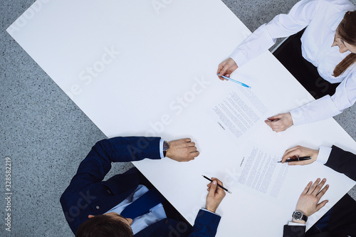 Group of business people and lawyer discussing contract papers sitting at the table, view from above. Businessman is signing document after agreement done photo