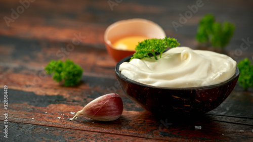 Mayonnaise sauce in a wooden bowl with egg, mustard, garlic and herbs photo