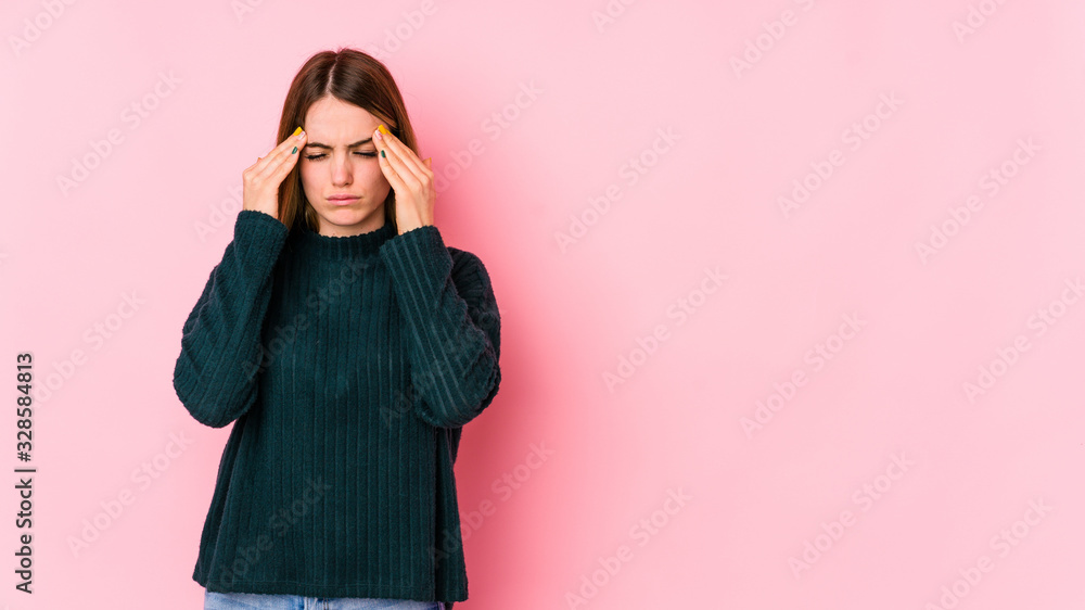 Obraz premium Young caucasian woman isolated on pink background having a head ache, touching front of the face.