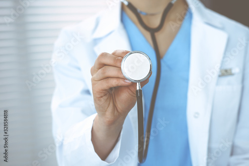 Unknown doctor woman holds stethoscope head, close-up. Physician ready to examine and help patient. Helping and insurance in health care, best treatment and medicine concept