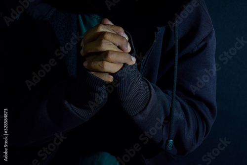 Young man worship and pray in cruch on dark black background. Christian faith or god concept. selective focus on finger