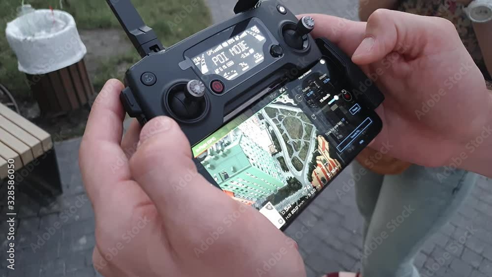 A man holding a remote control drone with a smartphone. On the screen view of the colorful houses A man holding a remote control drone with a smartphone. On the screen view of the colorful houses