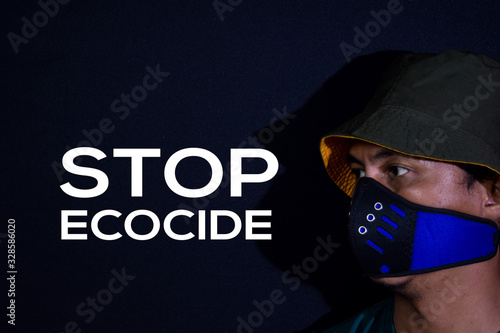 Bekasi. Indonesia. March 7 2020 : Young man use masker and stop ecocide write on dark black background. photo