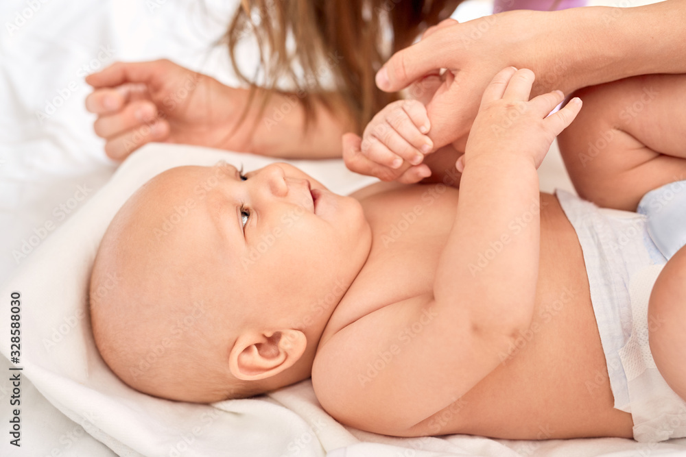 Young adult mom holding hands with little newborn child Young adult mom holding hands with little newborn child