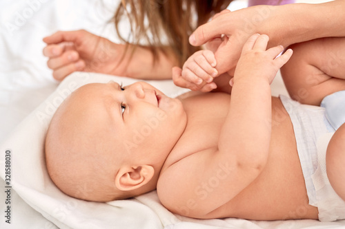 Young adult mom holding hands with little newborn child