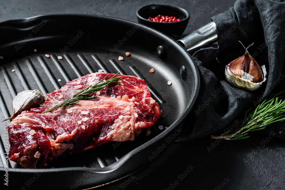 Marbled beef steak in a frying pan. Organic farm meat. Black background