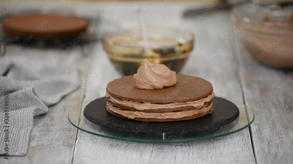 Step by step. Pastry chef making chocolate layer cake with prune filling. Confectioner puts cream on top of cake. Step by step. Pastry chef making chocolate layer cake with prune filling. Confectioner puts cream on top of cake.