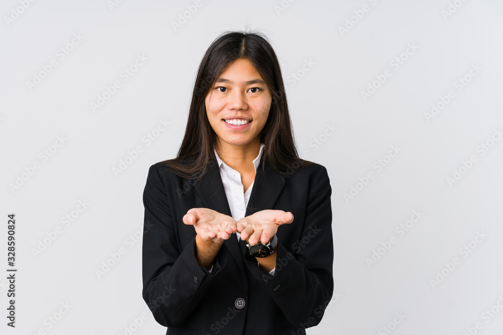 Young asian business woman holding something with palms, offering to camera. Young asian business woman holding something with palms, offering to camera.