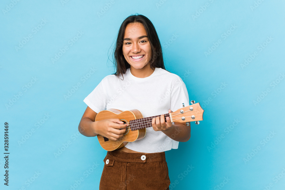 Young indian woman happy playing ukelele isolated Young indian woman happy playing ukelele isolated