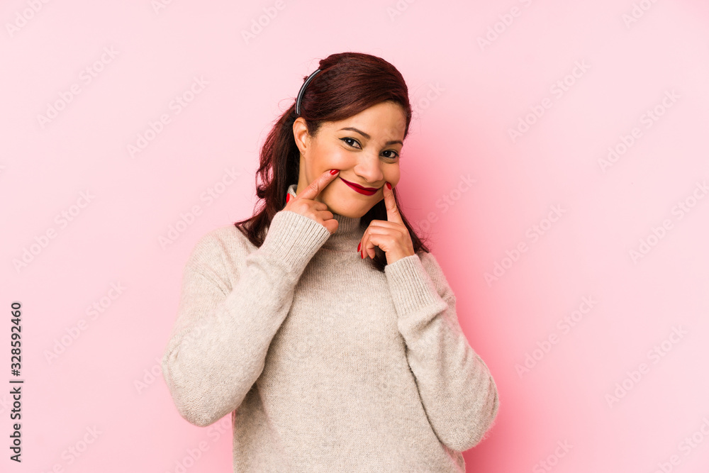 Middle age latin woman isolated on a pink background doubting between two options. Middle age latin woman isolated on a pink background doubting between two options.