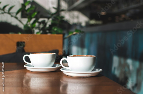 Two morning cups of coffee with nice foam on wooden background