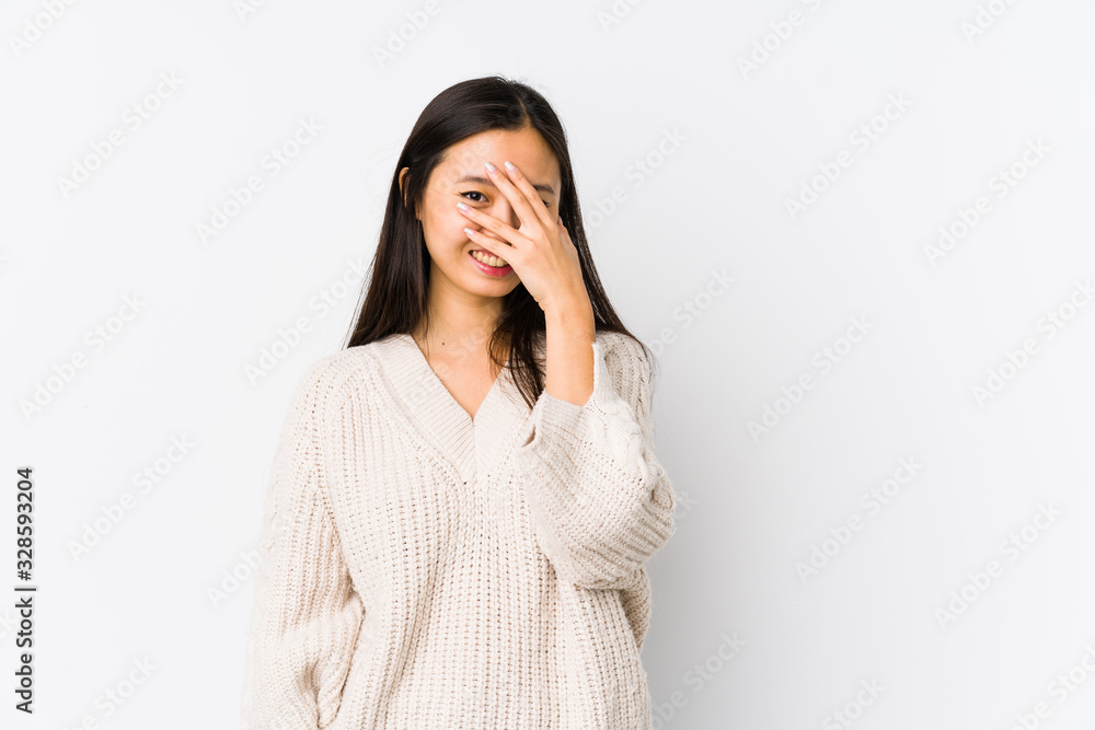Young chinese woman isolated blink at the camera through fingers, embarrassed covering face. Young chinese woman isolated blink at the camera through fingers, embarrassed covering face.