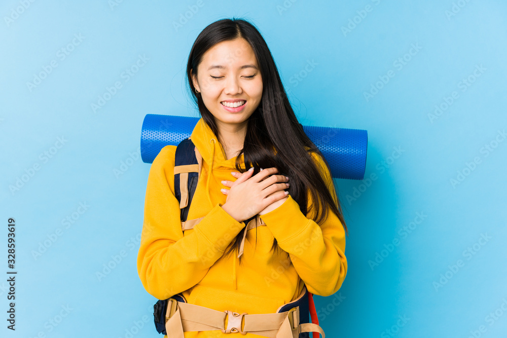 Young chinese backpacker woman isolated laughing keeping hands on heart, concept of happiness. Young chinese backpacker woman isolated laughing keeping hands on heart, concept of happiness.