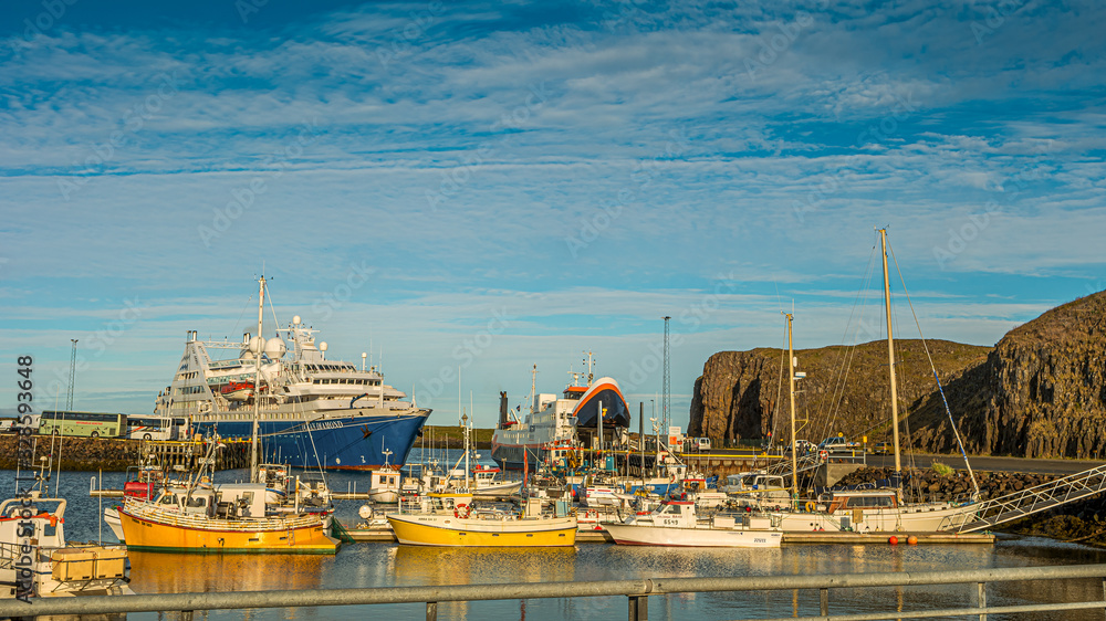 Panoramic view over sunset at Stykkisholmur (Stykkish) downtown and harbor with many fish restaurants, yachts, boats and a ferryboat towards Western Fjords, Iceland, summer