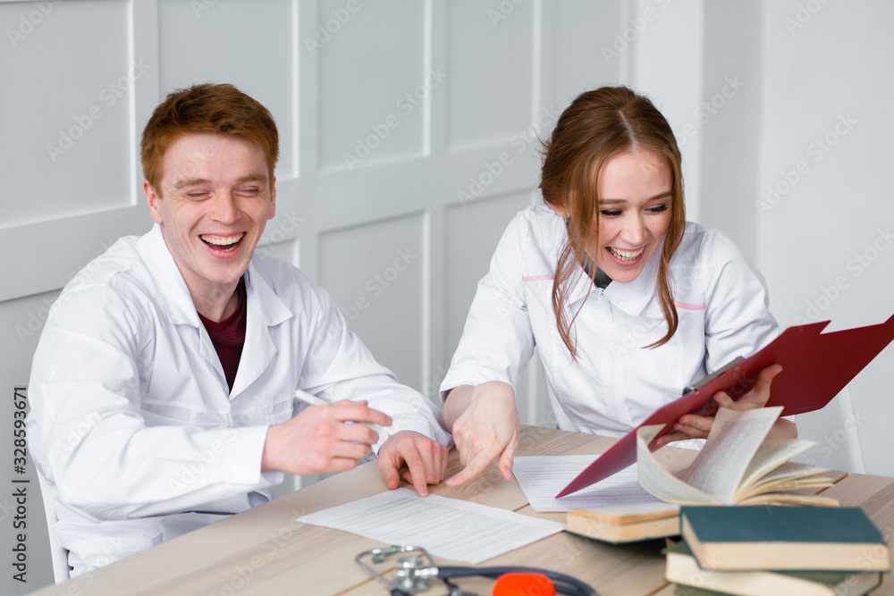 Fototapeta premium Desktop with books, phonendoscope and heart. Doctors take a break from hard work and look at the patients previous illnesses.