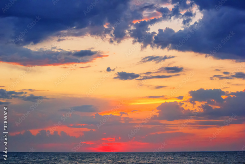 Fototapeta premium Beautiful red summer sunset (sunrise) with floating clouds over the sea