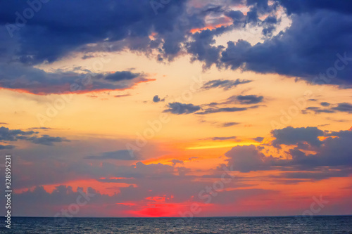 Beautiful red summer sunset (sunrise) with floating clouds over the sea