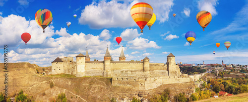 Autumn landscape - view of a medieval fortified castle on a hill with flying the hot air balloons, the town of Kamianets-Podilskyi, Ukraine