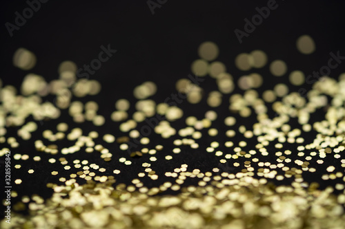 Beautiful Christmas light background. Abstract glitter bokeh and scattered sparkles in gold, on black